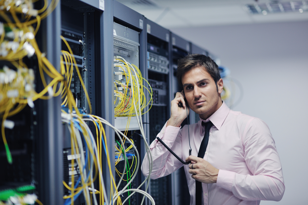young business man computer science engeneer talking by cellphone at network datacenter server room asking  for help and fast solutions and services